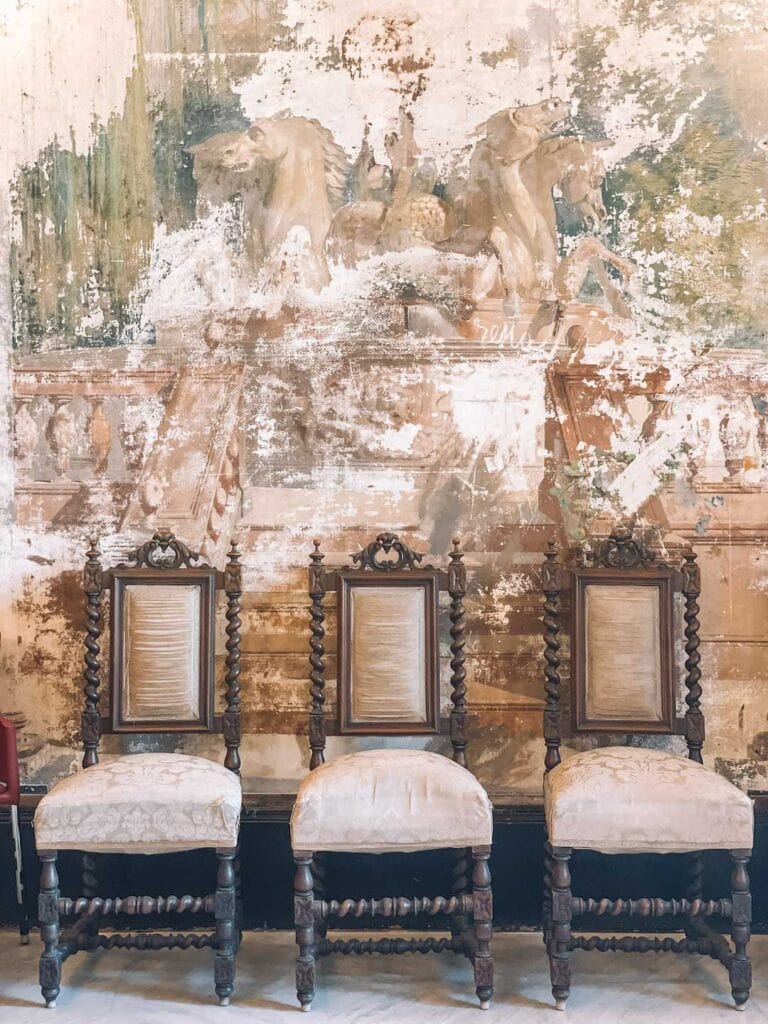 Old chairs and fading wallpaper inside mirto palace