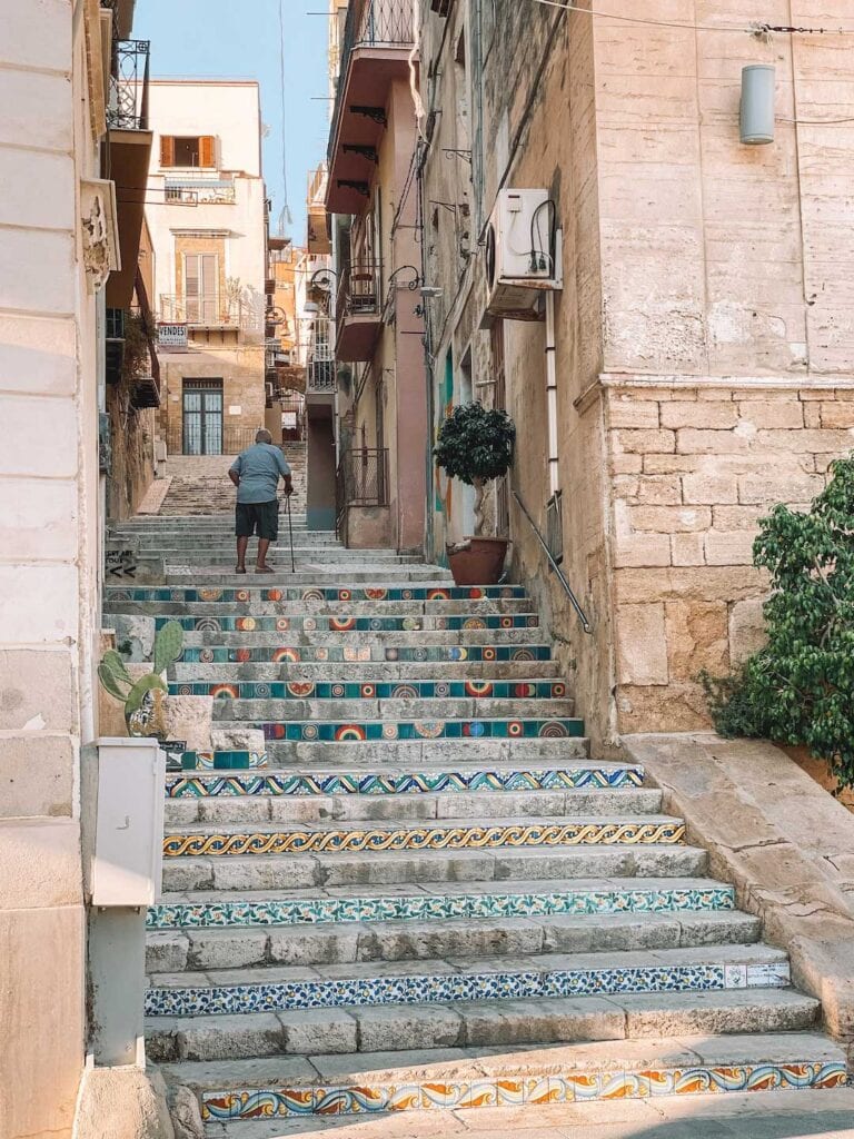 old man walking up tiled steps in Sciacca in southern sicily, day trips from Palermo