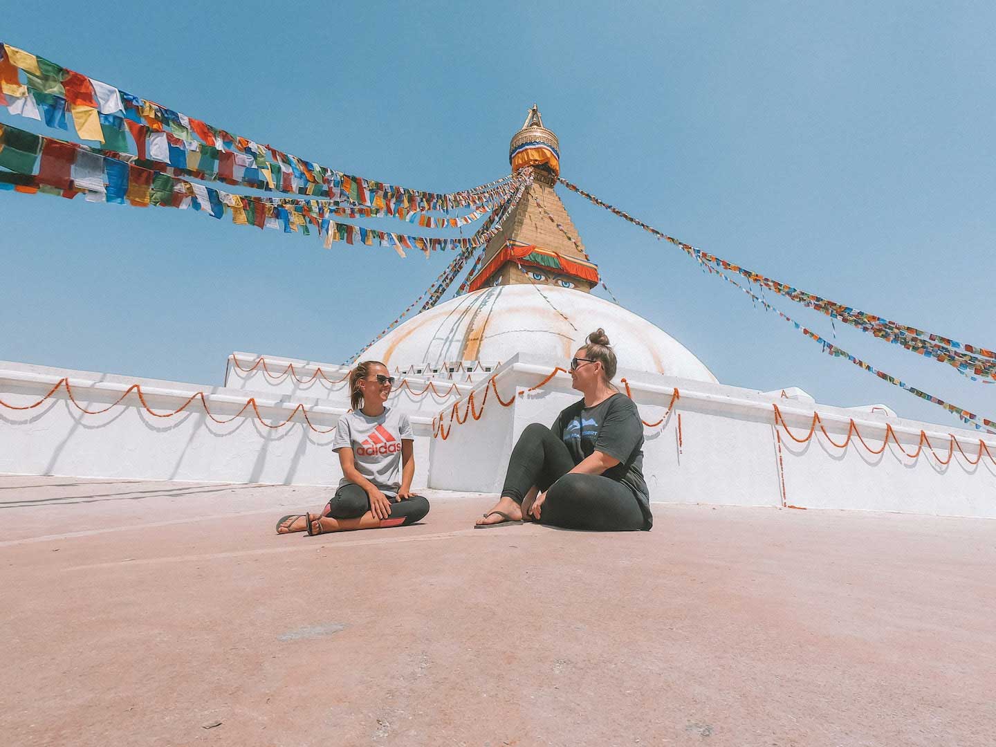 Sitting on the ground, in front of a large white stupa in Kathmandu, Nepal