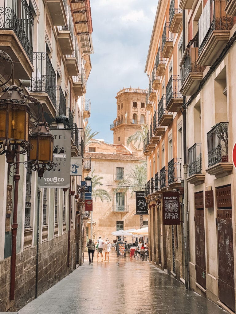 down a lanway is a beautiful view of the back side of Alicante Town Hall