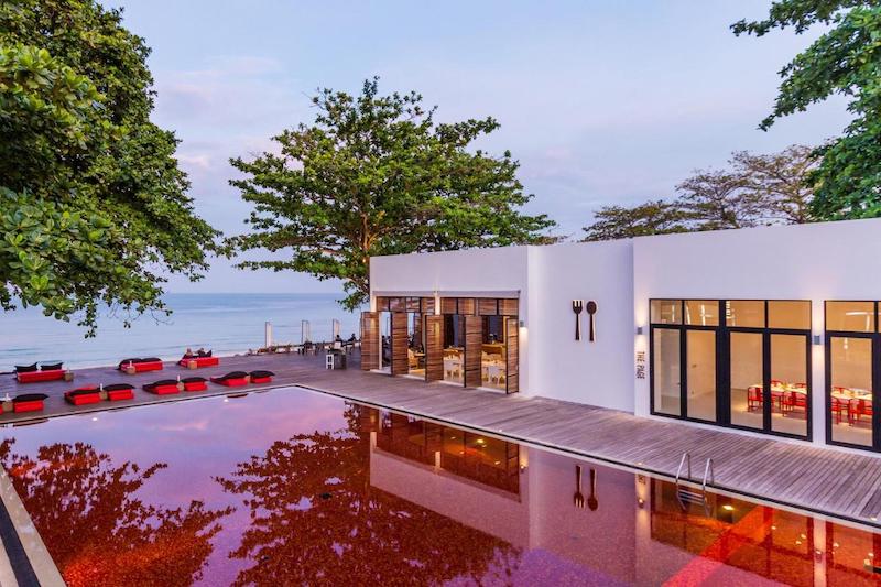 The Library's striking red pool, private beachfront, and rooms designed with artistic touches. Unique hotel in Thailand