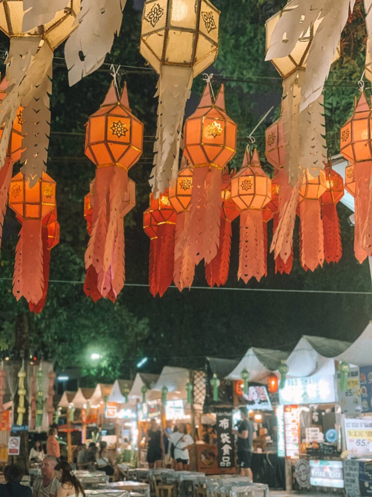 Colorful lanterns hanging above Chiang Mai night market at Lanna Square, filled with food stalls and people dining.