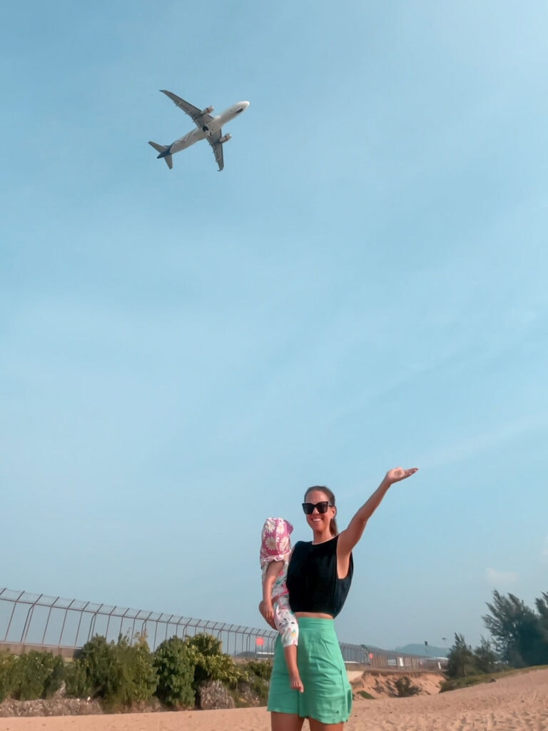 posing in front of a plane taking off from Phuket airport in Thailand