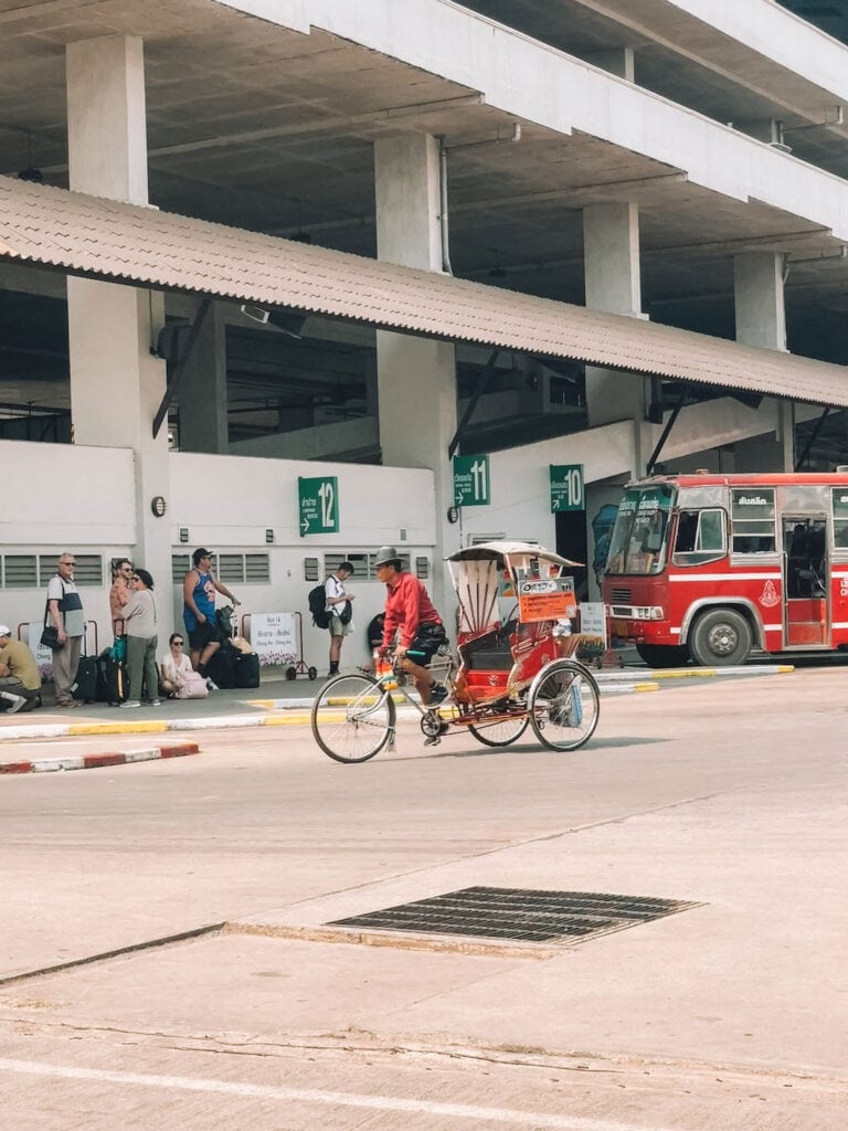 Platform at Chiang Rai Bus Terminal 1 with waiting passengers and a cycle rickshaw in front of the Green Bus platforms