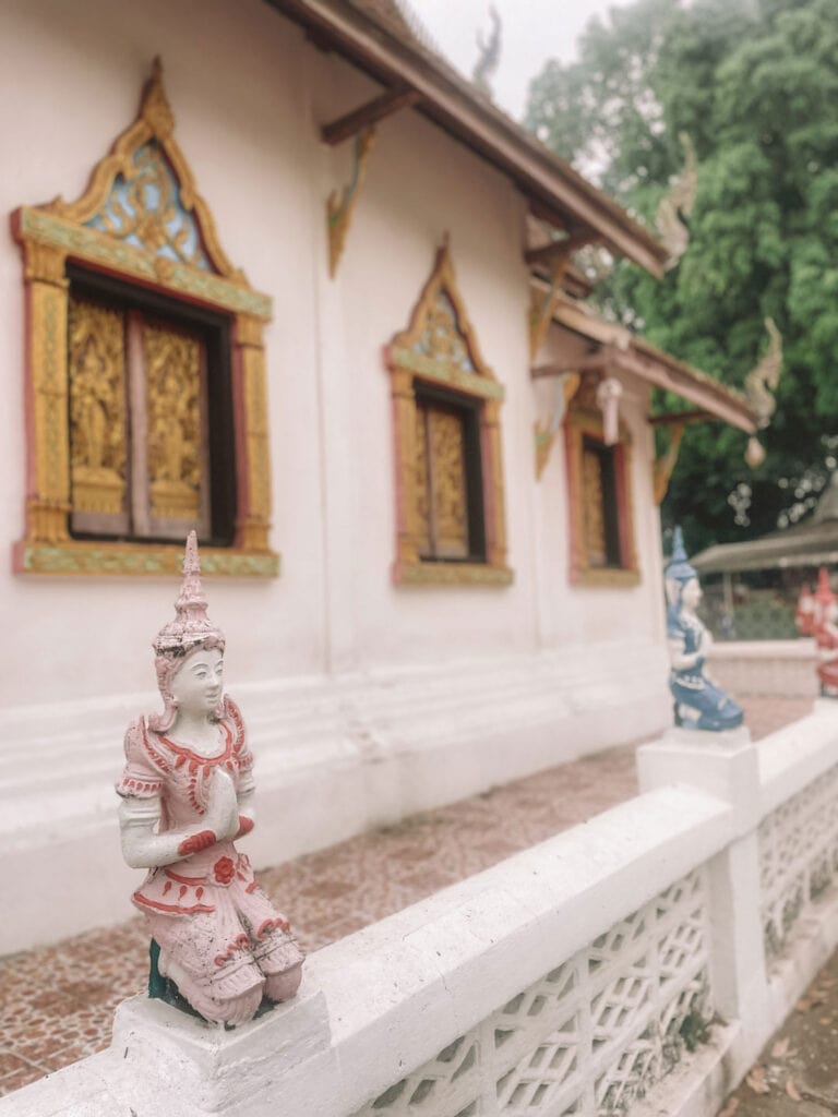 praying statues on the side of a tample in Pai, Northern Thailand