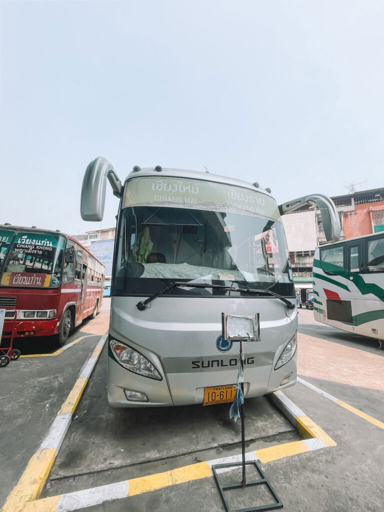 Green Bus from Chiang Rai to Chiang Mai parked at the terminal, ready for departure