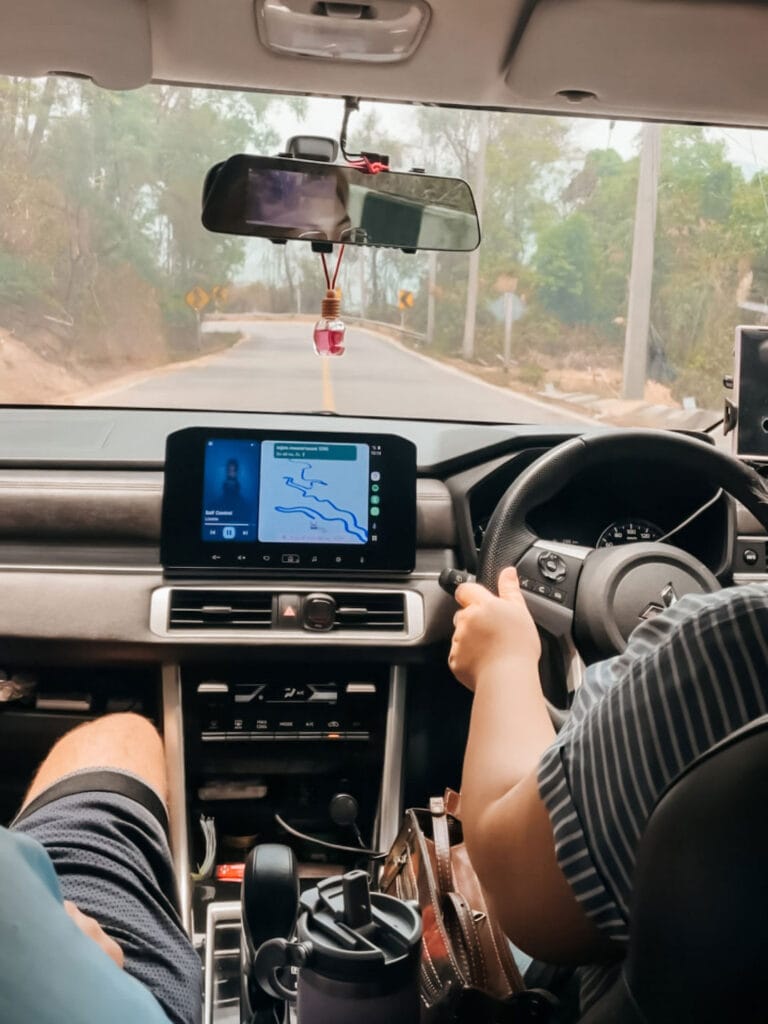 Driving from Chiang Mai to Pai with navigation showing winding mountain road, inside a car on the scenic 762-curve route in Northern Thailand.