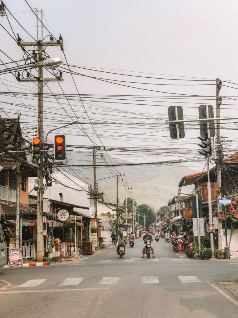 main street in Pai, two motorbikes are waiting at a red light