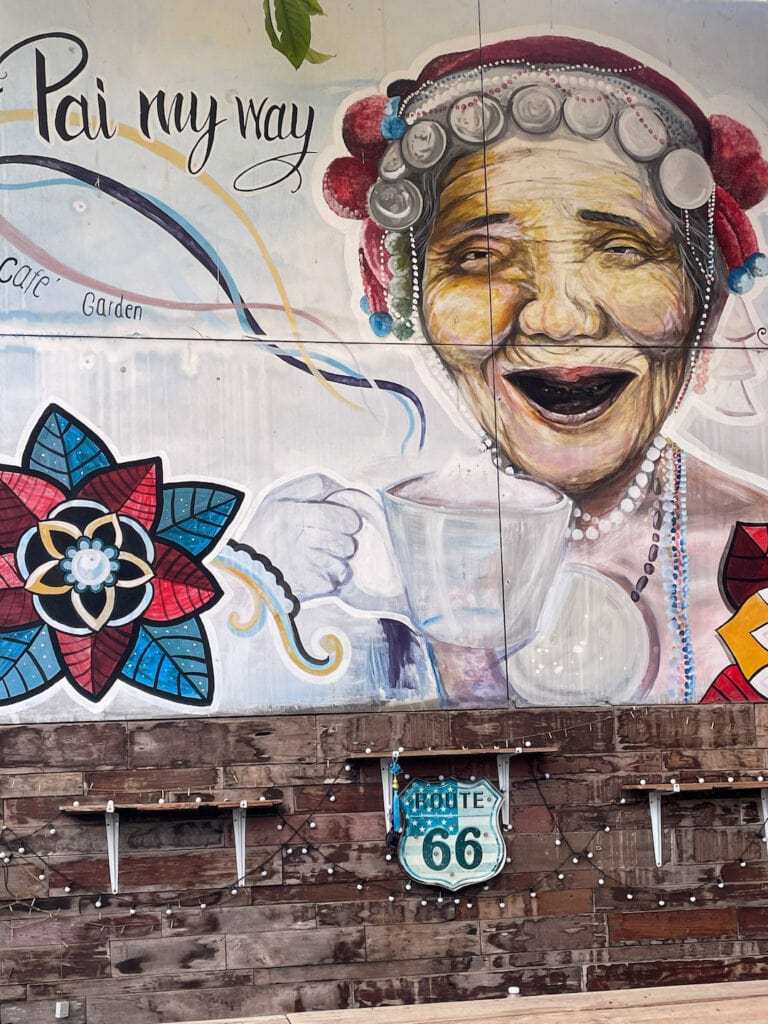 Street art of an old lady, drinking hot coffee in Pai Thailand