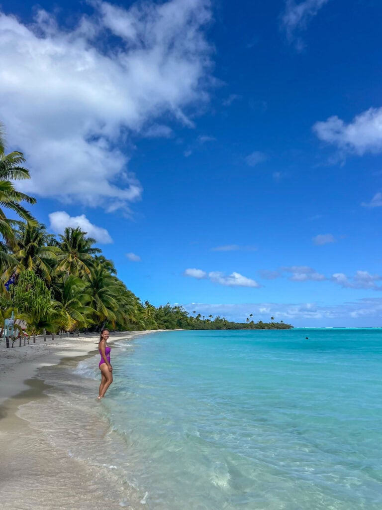 Scenic tropical beach on Akaiami, with palm trees and turquoise water under blue sky.