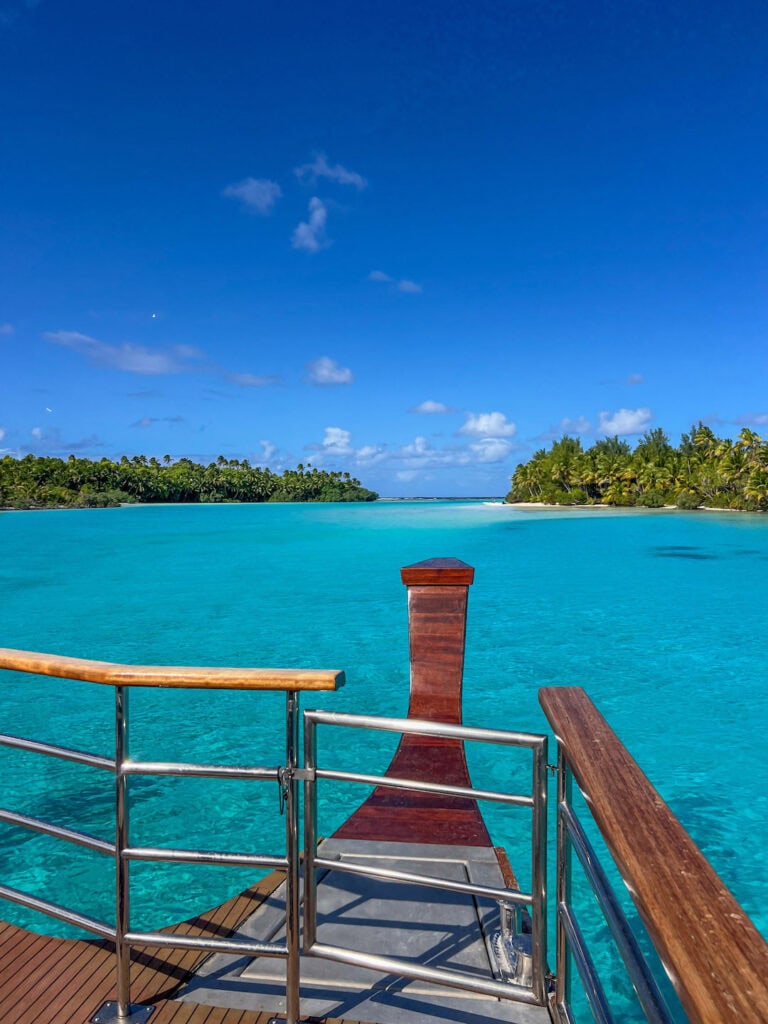 Vaka cruise boat arriving at One Foot Island, turquoise water and lush greenery in the distance