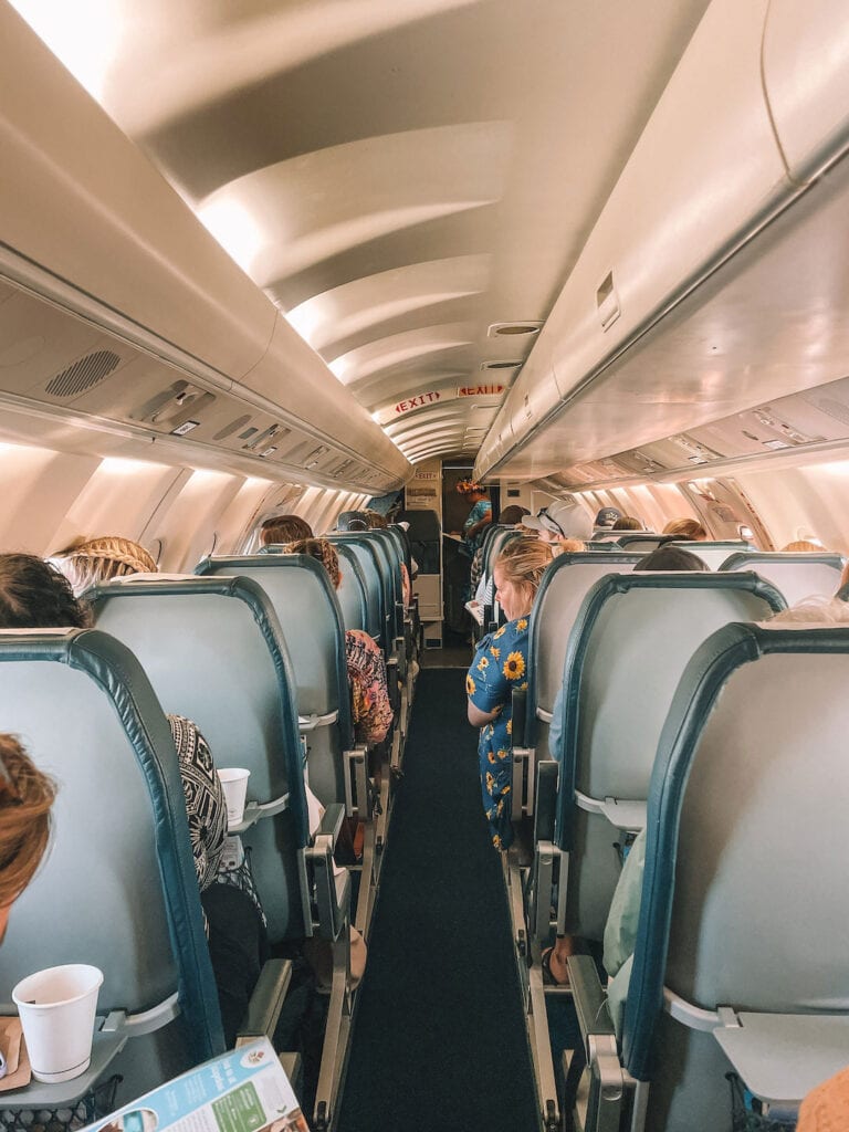 Air Rarotonga airplane interior with seated travelers and overhead compartments.