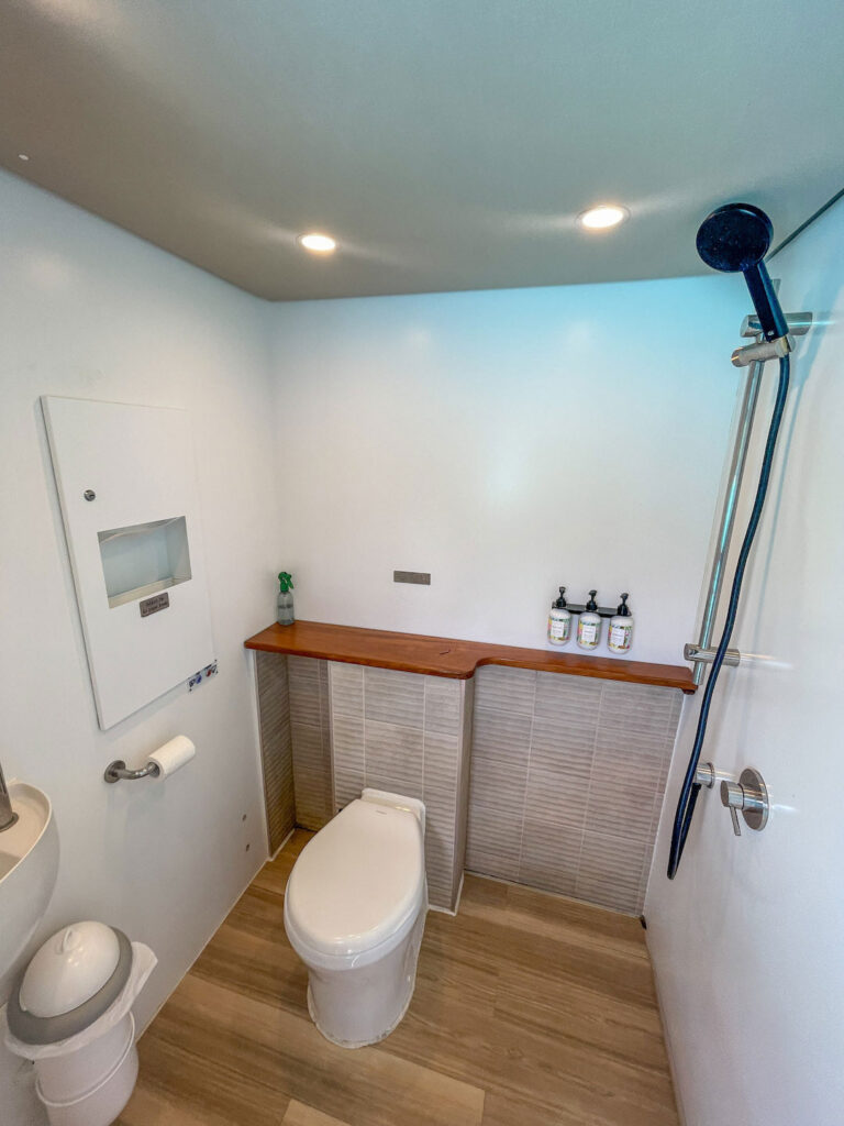 Contemporary bathroom featuring a toilet, shower, and minimalist design on board Vaka Cruise