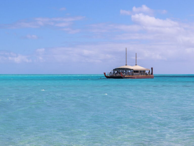 Calm turquoise sea with Vaka Cruise boat under a blue sky.