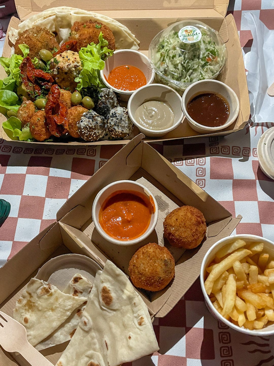 Variety of Mediterranean dishes with dips, fries, and salad at Falafel Shack in Raro